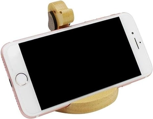 Macro shot of cute dog shaped solid wood phone stand with horizontal smartphone on white surface