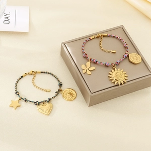 Detailed macro of handmade bohemian woven bracelets with golden heart and sun charms