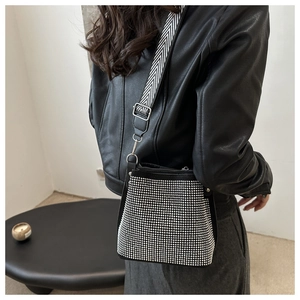 Detailed close-up of a black bucket bag with silver rhinestones and a wide striped strap