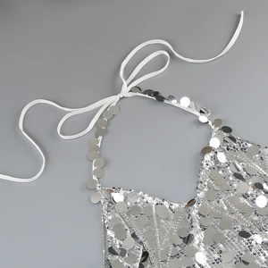 Detailed close-up of shiny silver sequins and white neck straps on the stylish dress