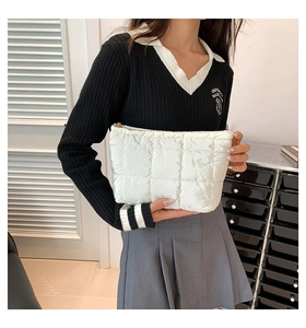 Close-up of white quilted handbag with metallic zipper and soft padded fabric texture