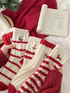 Close-up of thick red and white striped Christmas socks with festive embroidery patterns