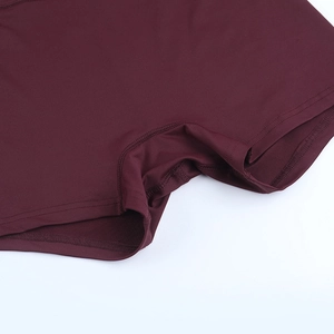 Detailed close-up of high-elasticity burgundy yoga shorts featuring reinforced flatlock seams