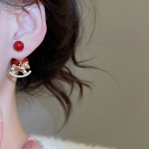 Close-up of 18K gold plated earring with a red bead and sparkling zircon horse pendant