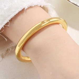 Close-up of polished gold hollow tube bangle showing high-gloss mirror finish on wrist