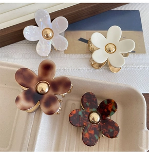 Detailed close-up of four floral hair claws in pearl, cream, and tortoiseshell finishes