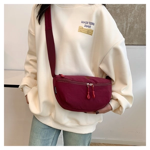 Detalle del bolso bandolera de nylon burdeos con correa ajustable en sudadera beige