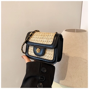 Detail of mini straw crossbody bag with black trim and golden flower metal clasp