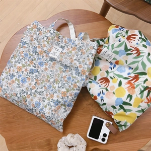 Borse tote in tela floreale su tavolo di legno con accessori per il tempo libero