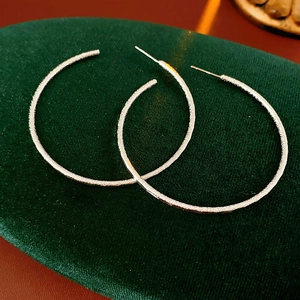 Dettaglio ravvicinato di orecchini a cerchio in argento opaco con finitura satinata