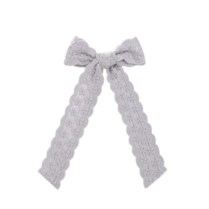 Detail of lavender lace hair bow clip featuring floral embroidery and long ribbons