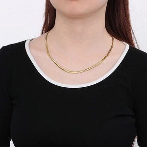 Gros plan d'un collier chaîne Figaro en acier inoxydable plaqué or 18 carats sur un mannequin