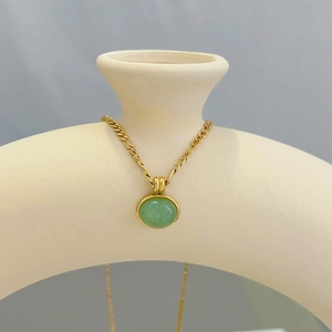 Close-up of green aventurine pendant necklace on beige ceramic art piece