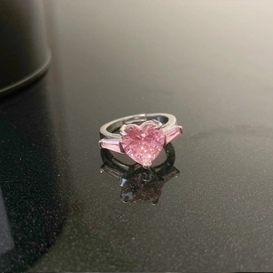 Detail of pink heart-shaped gemstone ring with side baguette stones on black mirror
