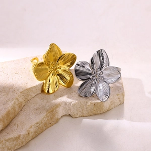 Vintage gold and silver stainless steel flower rings on a natural stone base