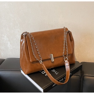 Detail of a brown vintage shoulder bag showing soft leather texture and metal lock buckle