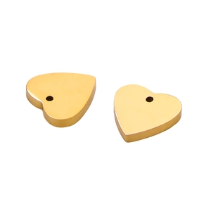 Dettaglio di ciondoli a cuore in metallo dorato con design minimalista e fori superiori