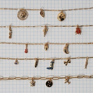 Flat lay of diverse gold stainless steel charms including heart, sun and sun pendants