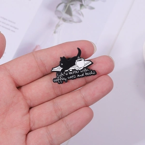 Cartoon black cat enamel pin featuring coffee and books with artistic typography