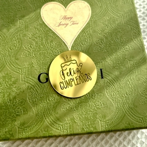 Detail of green embossed gift box with gold Feliz Cumpleanos seal and floral texture