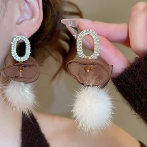 Detail of vintage oval stud earring with white rhinestones and soft fluffy fur ball