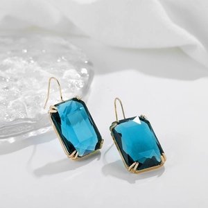 Details von blauen quadratischen Zirkon-Ohrringen mit Goldhaken auf weißem Hintergrund