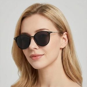 Close-up of a blonde woman wearing classic black round sunglasses with metal hinge detail