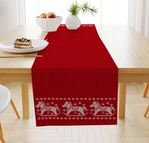 Detail of red linen Christmas table runner with white embroidered rocking horse and snowflake