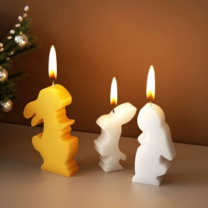 Dettaglio di tre candele a forma di coniglio accese in un ambiente domestico accogliente