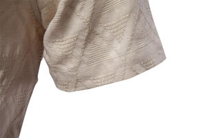 Detailed close-up of textured jacquard fabric sleeve on a beige short-sleeve shirt