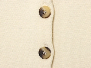 Detailed macro view of dark marble texture buttons on beige knitted slim fit fabric