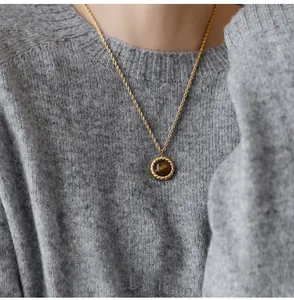 Detail of vintage gold rope chain necklace featuring a round tiger eye stone pendant