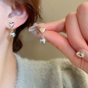 Vue détaillée des boucles d'oreilles cœur avec perle grise montrant l'effet porté sur l'oreille