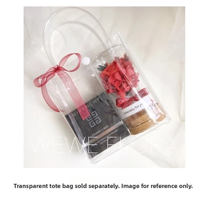 Close-up of transparent PVC gift bag with red preserved flower bottle and elegant ribbon