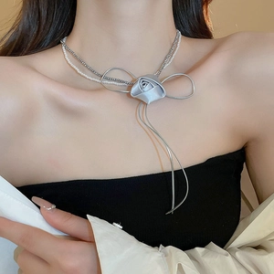 Detail of double-layer necklace with grey fabric rose, pearl beads, and metal bow tassel