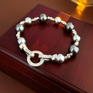 Close-up of grey pearl bracelet with zircon clasp on dark wood jewelry box stand