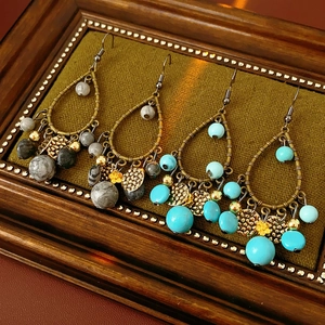 Detailed view of vintage bamboo-style drop earrings with turquoise and gold beads in a frame