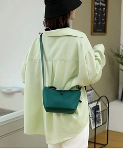 Dark green nylon dumpling crossbody bag shown on model with adjustable shoulder strap