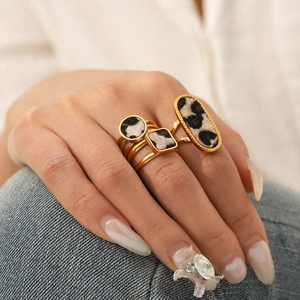 Nahaufnahme von goldenen Ringen mit Leopardenmuster, getragen von einem Model