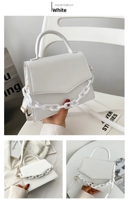 Detail of white fashion crossbody bag featuring a geometric V-cut flap and thick chain link