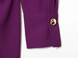 Détail de la manche violette avec texture de tissu fine et bouton doré poli