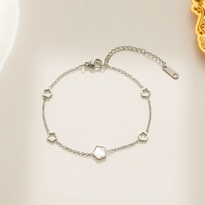 Silver titanium steel bracelet featuring five white shell flowers and an 18KGP tag