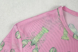 Detail of pink mesh fabric featuring a vivid green lobster print and round neckline