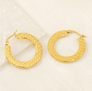 Detail view of large gold hoop earrings featuring a retro hammered star texture and pin clasp