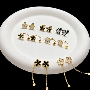 Detailed collection of gold floral earrings with black and white enamel on a white plate