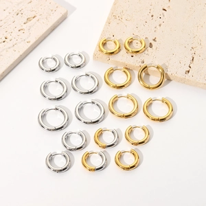 Minimalist high-polished 18K gold and silver titanium steel hoop earrings on stone slab
