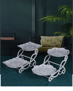 Detail of white two-tier dessert stands with ornate curly metal frames and hollow patterns