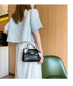 Detail of black crocodile pattern bag with silk scarf handle and gold chain strap