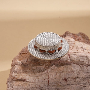 Detail of silver metallic sun hat brooch with woven texture and brown leather cord detail