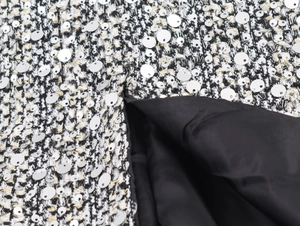 Macro shot of black and white tweed fabric with shiny silver sequins and soft lining